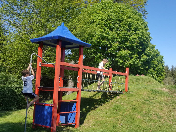 Kinder am Kletterturm mit blauem Dach auf dem Spielplatz des Campingplatzes Waldeck
