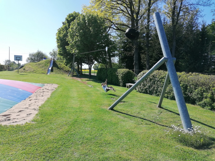 Kind auf der Seilbahn am Spielplatz des Campingplatzes Waldeck mit Basketballkorb und Hüpfkissen
